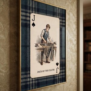 May include: A framed rectangular wall art piece featuring a playing card design with a blue and black plaid background. The card depicts a person ironing fabric on a table, labeled with the letter J, a spade symbol, and the text JACK OF THE CLOTH.