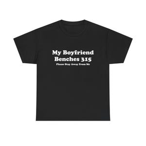 Peut inclure: T-shirt noir avec texte blanc : « My Boyfriend Benches 315 » et « Please Stay Away From Me ». Le t-shirt à col rond est en matière douce. Le texte est en gras, en police sans-serif.