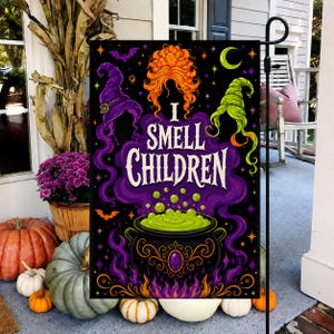 May include: A rectangular garden flag with a black background featuring a central black cauldron bubbling with green liquid. Above the cauldron, the text reads I SMELL CHILDREN in white. The design includes orange hair, purple and green witch hats, bats, and a crescent moon.