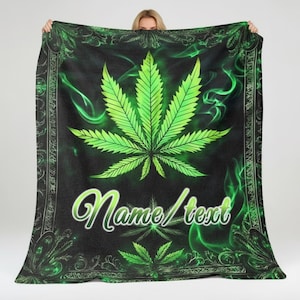 May include: Black blanket with a large, bright green cannabis leaf design. The blanket features a decorative border and the words "Name/Text" in a cursive font. Green smoke-like accents surround the leaf.