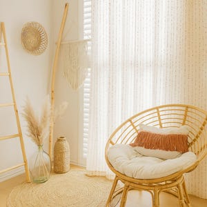 Puede incluir: Un interior acogedor de estilo bohemio con una silla redonda de rat&aacute;n, un coj&iacute;n blanco y una almohada con flecos. Una alfombra tejida, un jarr&oacute;n decorativo con hierba de la pampa y una escalera de madera se suman a la est&eacute;tica natural de la habitaci&oacute;n. Un tapiz de pared tejido y una decoraci&oacute;n de pared redonda completan el look.
