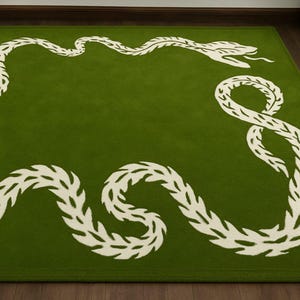 May include: A rectangular green rug featuring a white snake design. The snake's body is formed from leaf-like shapes, with a detailed head and forked tongue. The rug is designed to be placed on a floor.