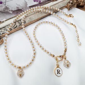 Conjunto de collar y pulsera de perlas de agua dulce con corazón de circonita y dije de letra personalizado. Elegante joyería artesanal.