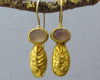 May include: A pair of gold earrings with a textured leaf design and a light pink oval gemstone.