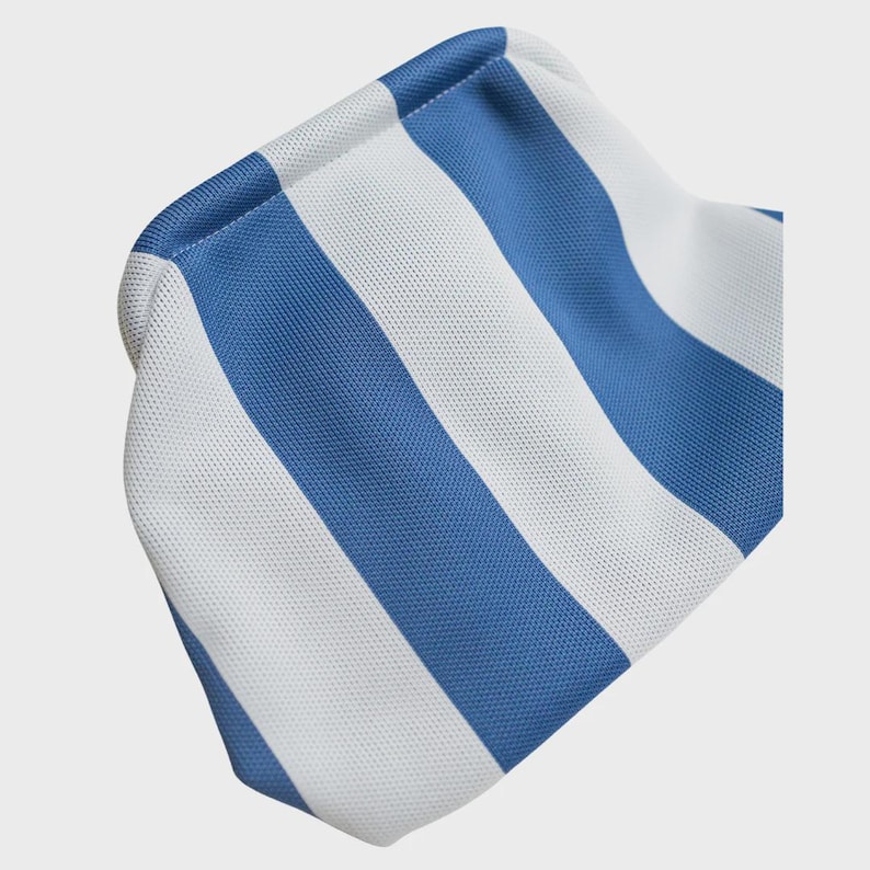 May include: A small pouch featuring a repeating vertical stripe pattern in alternating shades of bright blue and crisp white. The fabric has a visible, fine-textured weave, and the pouch is constructed with a rounded, soft-sided frame design.