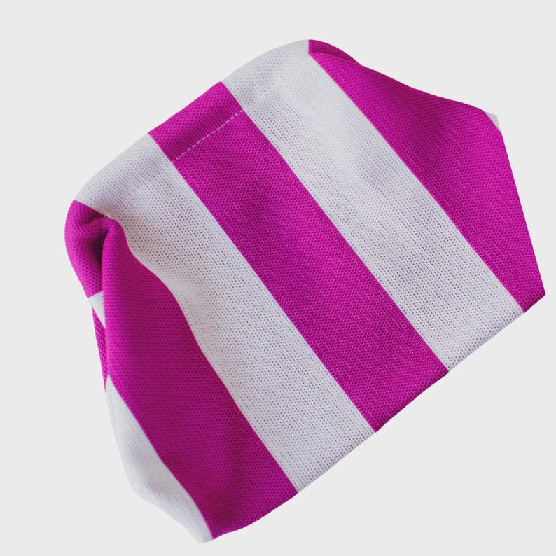 May include: A beanie hat featuring a bold, repeating pattern of vertical stripes in vibrant magenta and crisp white. The fabric has a distinct, fine-knit texture throughout, creating a structured yet flexible form that maintains its shape.