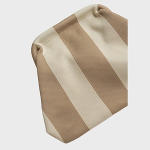 May include: A pouch featuring a knitted texture with alternating vertical stripes in beige and cream. The bag has a rounded top edge and a structured, slightly curved shape, showcasing a consistent woven pattern throughout the entire exterior surface.