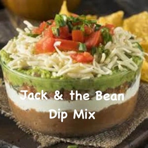 May include: A layered dip in a clear glass bowl with a green avocado layer, a white sour cream layer, a brown bean layer, and a red tomato and shredded cheese topping. The dip is labeled "Jack & the Bean Dip Mix".