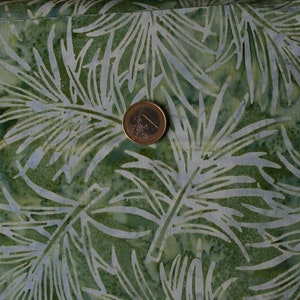 Może przedstawiać: Zielony materiał z białym wzorem liści. Materiał ma wzór w stylu batik.