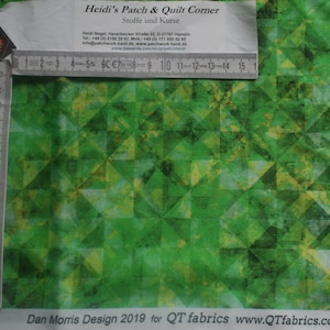 Op de afbeelding: Groene stof met een geometrisch patroon van overlappende driehoeken. De stof heeft een subtiele, textuur. De tekst "Dan Morris Design 2019 for QT fabrics www.QTfabrics.com" is onderaan de afbeelding gedrukt.