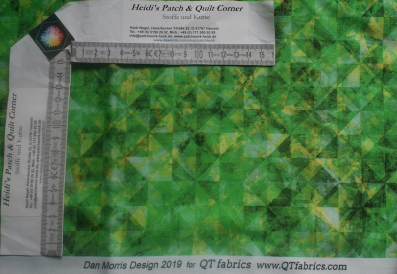 Op de afbeelding: Groene stof met een geometrisch patroon van overlappende driehoeken. De stof heeft een subtiele, textuur. De tekst "Dan Morris Design 2019 for QT fabrics www.QTfabrics.com" is onderaan de afbeelding gedrukt.