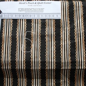 May include: Black fabric with thin white and beige stripes. The stripes are outlined with a small brown pattern. A ruler is visible at the top of the image.