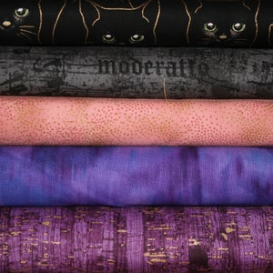 May include: Five different fabric swatches stacked on top of each other. The top swatch is black with a gold metallic print of black cats. The second swatch is a dark gray with a distressed look and the word "moderati" printed in white. The third swatch is a light pink with a subtle gold metallic dot pattern. The fourth swatch is a purple with a tie-dye pattern. The bottom swatch is a dark purple with a gold metallic print of a textured pattern.
