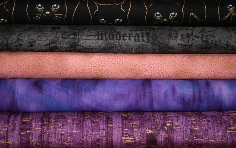 May include: Five different fabric swatches stacked on top of each other. The top swatch is black with a gold metallic print of black cats. The second swatch is a dark gray with a distressed look and the word "moderati" printed in white. The third swatch is a light pink with a subtle gold metallic dot pattern. The fourth swatch is a purple with a tie-dye pattern. The bottom swatch is a dark purple with a gold metallic print of a textured pattern.