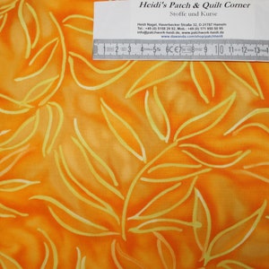 May include: Orange fabric with a yellow leaf pattern. The fabric is measured with a ruler in inches.