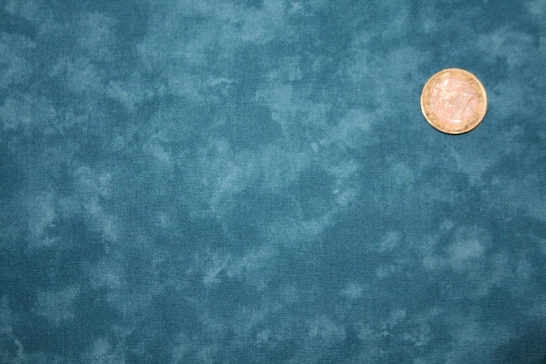 May include: A close-up of a teal blue fabric with a mottled, cloudy pattern. The fabric has a subtle texture and a soft, faded look.