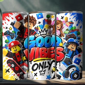 Puede incluir: Un vaso cilíndrico con un estampado gráfico colorido de personajes estilo bloque, mandos de videojuegos, auriculares y un monopatín. El texto GOOD VIBES ONLY está impreso en el centro con un icono de corona encima y debajo de las palabras.