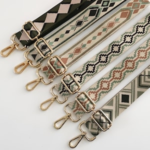 May include: Six patterned bag straps with gold-coloured metal clasps. The straps feature geometric designs in shades of green, brown, and cream. Each strap has a different pattern, including diamonds, chevrons, and geometric shapes. The straps are arranged diagonally.