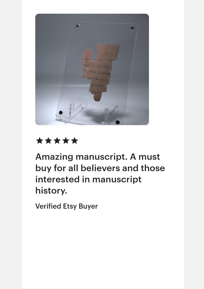 May include: A fragment of an ancient manuscript, displayed in a clear acrylic stand. The text is in a faded brown color, and the stand is supported by a clear base. The image includes the text: "Amazing manuscript. A must buy for all believers and those interested in manuscript history."