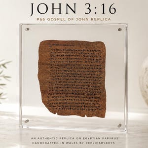 Peut inclure: Un cadre rectangulaire en acrylique transparent contenant un fragment de papyrus brun avec du texte grec noir. Le texte en haut indique JOHN 3:16 P66 GOSPEL OF JOHN REPLICA. Sous le cadre, le texte indique AN AUTHENTIC REPLICA ON EGYPTIAN PAPYRUS.