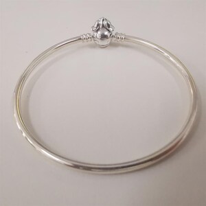 Puede incluir: Una pulsera de plata con un cierre decorativo. El cierre presenta un dise&ntilde;o redondeado y detallado. La pulsera es circular y parece estar hecha de metal brillante. El dise&ntilde;o es simple y elegante. Di&aacute;metro: aproximadamente 6,5 cm.