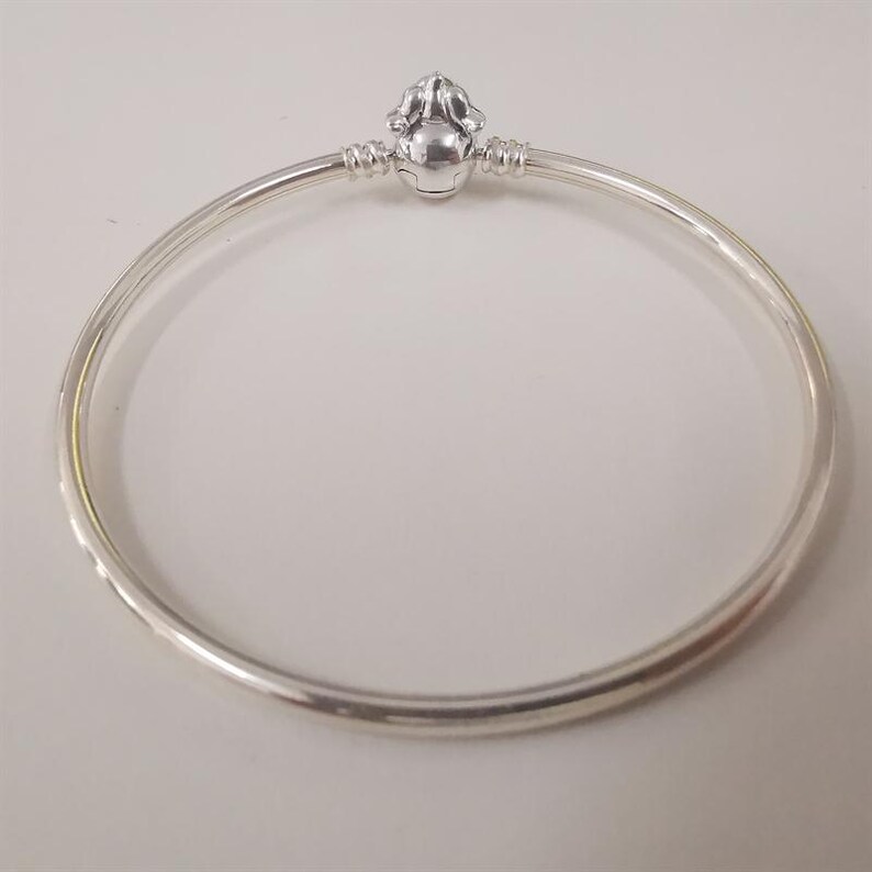 Puede incluir: Una pulsera de plata con un cierre decorativo. El cierre presenta un dise&ntilde;o redondeado y detallado. La pulsera es circular y parece estar hecha de metal brillante. El dise&ntilde;o es simple y elegante. Di&aacute;metro: aproximadamente 6,5 cm.