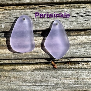 May include: Two periwinkle-coloured, teardrop-shaped pendants with small holes at the top. The pendants are displayed on a weathered wooden surface. The word "Periwinkle" is written in purple text.