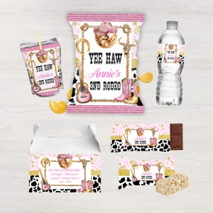 Puede incluir: Un conjunto de artículos para fiestas con temática de rodeo. Incluye una bolsa de jugo, una bolsa de patatas fritas, una botella de agua, una caja de regalo, una barra de chocolate y una barra de arroz inflado. El diseño presenta un estampado de vaca rosa, dorado y negro con el texto "Yee Haw Annie's 2nd Rodeo."