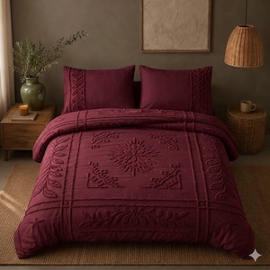 May include: A deep burgundy bedding set featuring a duvet cover and two matching pillowcases. The fabric displays a raised, tufted texture with intricate geometric and botanical patterns, including central star motifs and leaf-like borders.