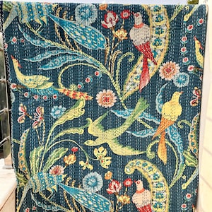 Könnte beinhalten: Eine teal-farbene Steppdecke mit einem lebendigen Vogel- und Blumenmuster. Das Design zeigt bunte Vögel, Blumen und Blätter in Gelb-, Rot- und Blautönen. Die Steppdecke besteht aus einem weichen Material und hat einen genähten Rand.