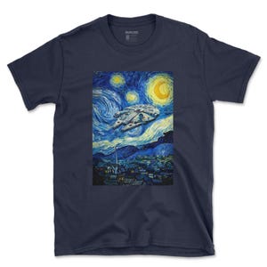 May include: A navy blue short-sleeve t-shirt featuring a graphic print of a spaceship flying through a swirling, starry night sky above a small town. The artwork mimics a post-impressionist painting style with bold brushstrokes in shades of blue, yellow, and black. The brand name SNARKSIDE is printed on the inside neck label.