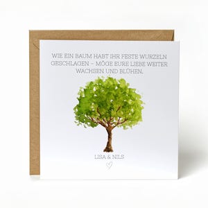 Könnte beinhalten: Eine quadratische Grußkarte mit einer Aquarellillustration eines grünen Baumes mit braunem Stamm. Die Karte hat deutschen Text und befindet sich in einem braunen Umschlag. Der Text lautet: "WIE EIN BAUM HABT IHR FESTE WURZELN GESCHLAGEN - MÖGE EURE LIEBE WEITER WACHSEN UND BLÜHEN."