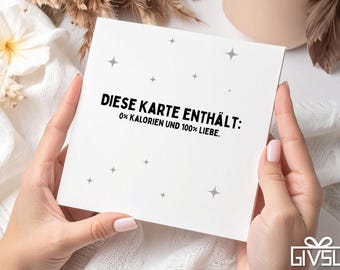 Puede incluir: Una tarjeta de felicitación blanca con el texto "DIESE KARTE ENTHÄLT: 0% KALORIEN UND 100% LIEBE." es sostenida por una persona. La tarjeta tiene un diseño sencillo con acentos de estrellas grises. El fondo incluye flores y un jarrón de color neutro.