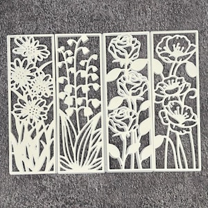 May include: Four white metal floral panels. Each panel features a different floral design: daisies, lily of the valley, roses, and poppies. The panels are rectangular with intricate cut-out details, perfect for crafting or decor.
