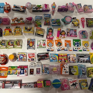 Può includere: Una collezione di vari giocattoli e oggetti da collezione in miniatura, tra cui macchinine, bambole e cubi di Rubik. I giocattoli sono confezionati in scatole e contenitori colorati, alcuni con personaggi e marchi riconoscibili. L'immagine include il testo "Razor", "Glitter", "Beat Parents" e "Color Need Doh".
