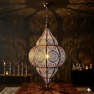 May include: An elaborate bronze pendant light, featuring detailed openwork patterns. The lamp hangs from a chain and casts decorative shadows. The design is inspired by Moroccan or Middle Eastern styles, suitable for home decor.