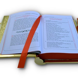 Puede incluir: Un libro abierto, con bordes dorados, con un marcador de cinta roja. El libro tiene una cubierta de cuero rojo y p&aacute;ginas blancas con texto negro. El texto de la p&aacute;gina derecha enumera "Milagros de Nuestro Santo Salvador y los Ap&oacute;stoles" con una lista numerada de milagros.