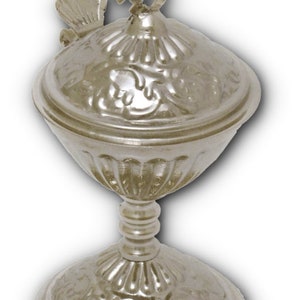 May include: A silver, ornate, religious chalice with a lid and a cross on top. The chalice has a decorative, floral design.