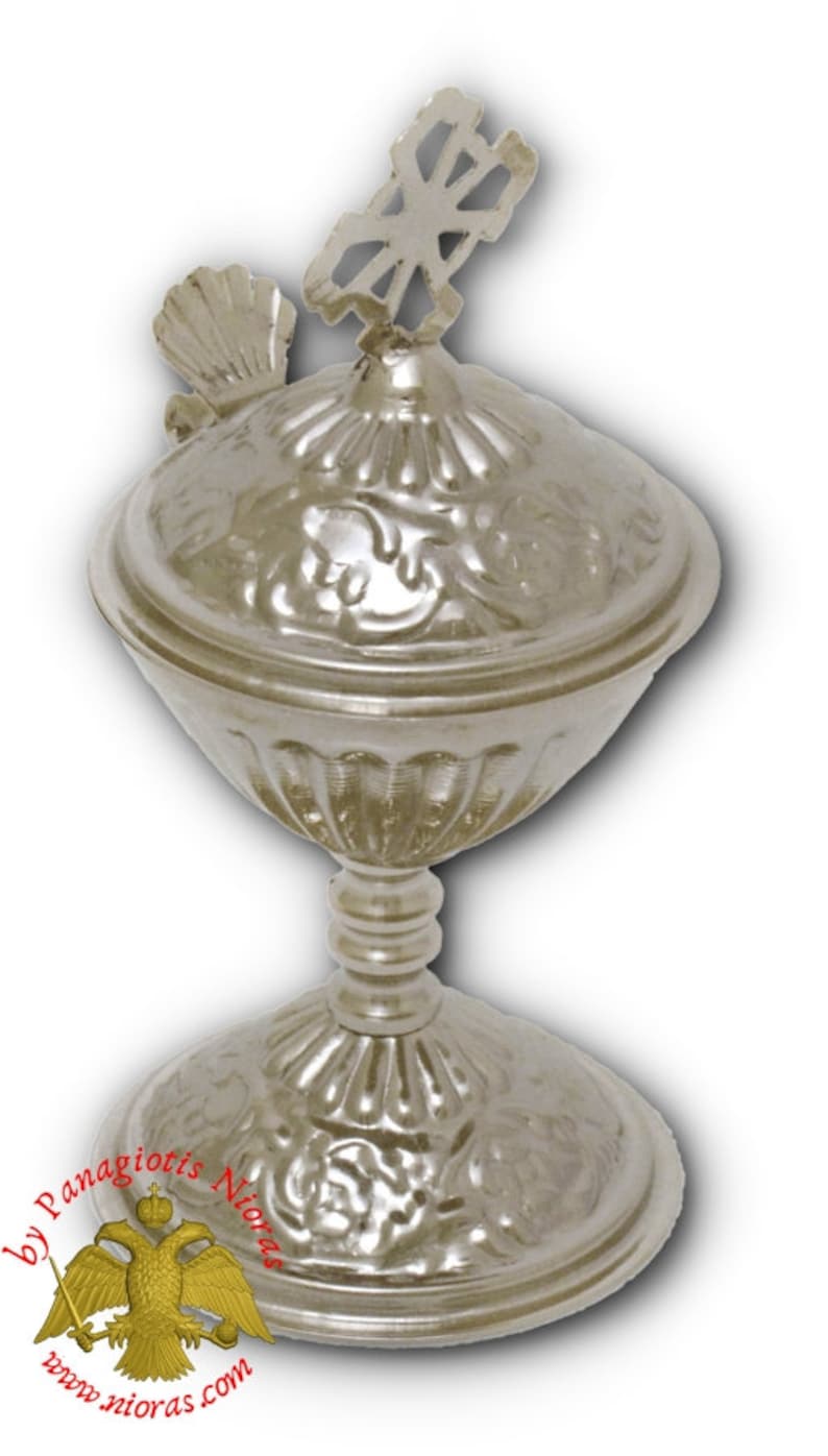 May include: A silver, ornate, religious chalice with a lid and a cross on top. The chalice has a decorative, floral design.