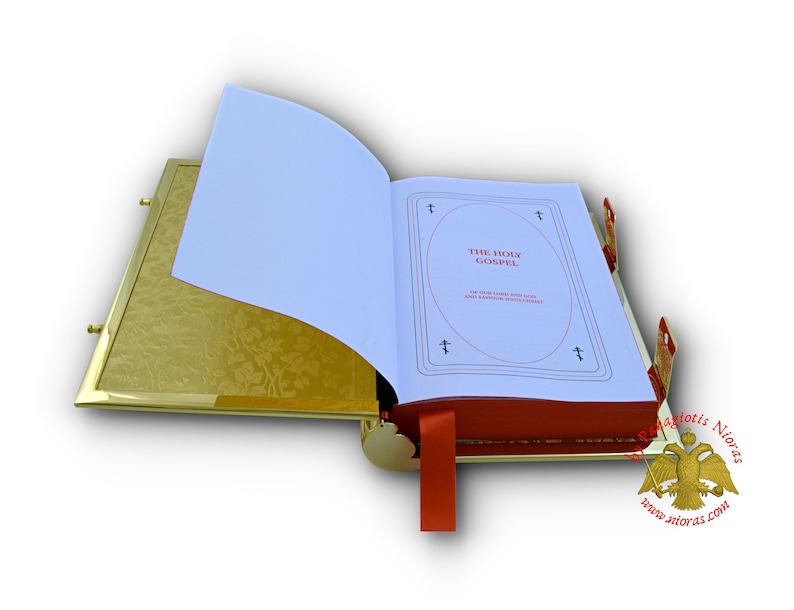 Puede incluir: Un libro encuadernado en cuero rojo con bordes dorados, con una p&aacute;gina blanca abierta. La p&aacute;gina tiene las palabras "The Holy Gospel" impresas en negro. El libro est&aacute; apoyado sobre una superficie dorada.