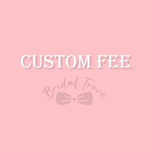 Op de afbeelding: Een roze achtergrond met de woorden "CUSTOM FEE" in witte, omrande letters. Onder de tekst staat het logo van "Bridal Trove" in een cursief lettertype met een strik.