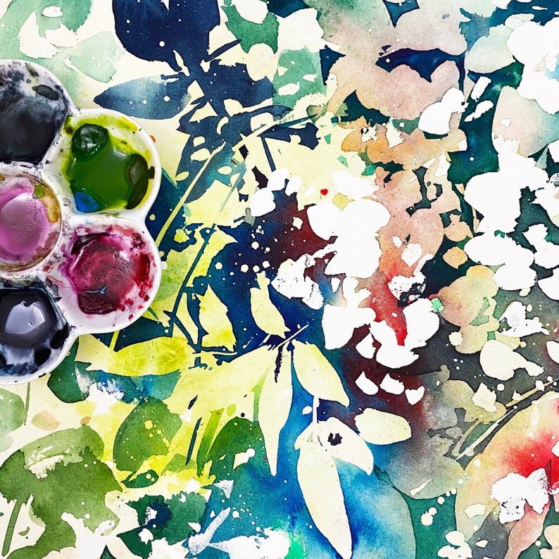 May include: A watercolor painting of a floral design with a palette of paint colors in the bottom left corner. The painting features a variety of colors, including blue, green, yellow, pink, and white.