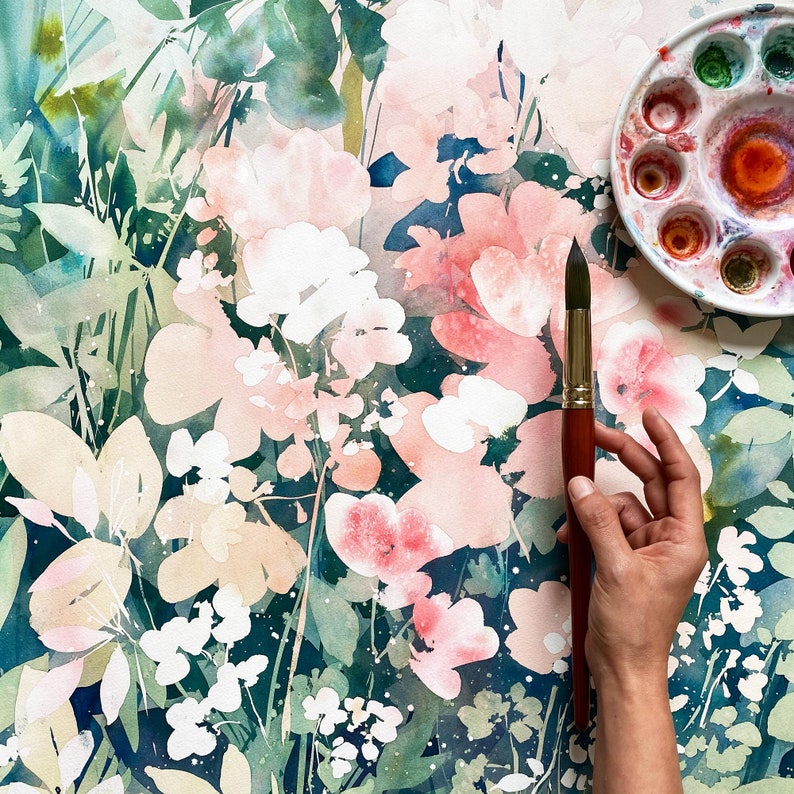 Op de afbeelding: Aquarel schilderij van roze en witte bloemen met groene bladeren op een donkerblauwe achtergrond. Een rond palet met verschillende verfkleuren en een penseel met een houten handvat bevinden zich in de rechterbovenhoek.