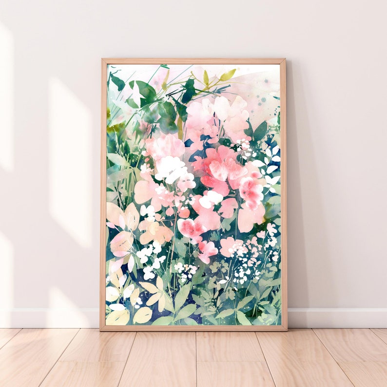 Op de afbeelding: Ingelijste aquarelprint met bloemen in roze, witte en groene tinten. Het bloemkunstwerk is geplaatst tegen een donkerblauwe achtergrond, met een houten frame. De print wordt gepresenteerd op een lichtgekleurde muur.
