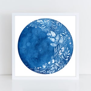 Puede incluir: Una pintura de acuarela de una luna azul con dise&ntilde;os florales blancos. La luna est&aacute; rodeada de un fondo blanco.