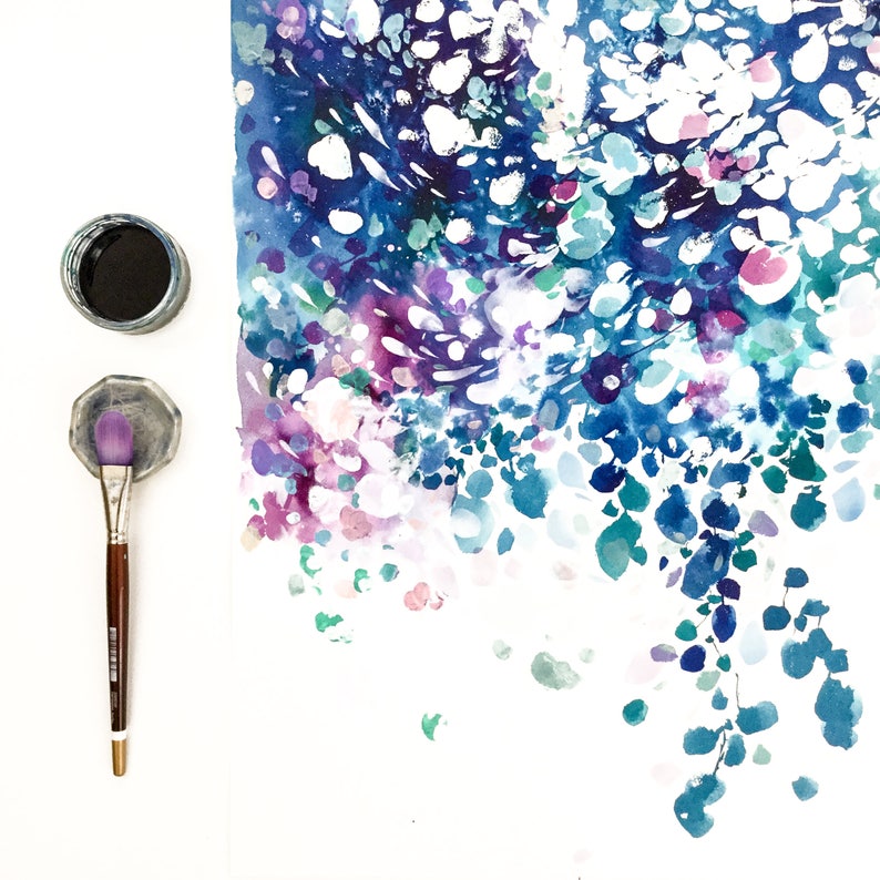 May include: An overhead shot of art supplies and a watercolor painting. The painting features a blend of blue, purple, and white watercolor paint. A jar of black paint, a brush, and a palette are also visible.