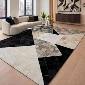 May include: A large rectangular area rug featuring a geometric patchwork design composed of square tiles in shades of black, white, cream, and grey. The rug displays a pattern of large triangles and smaller squares, creating a bold contrast.