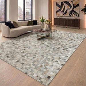 Può includere: Un grande tappeto rettangolare caratterizzato da un design a patchwork composto da piccole tessere quadrate in varie tonalità di grigio, bianco, beige e marrone. Il tappeto presenta una superficie strutturata con un motivo a griglia ripetuto.