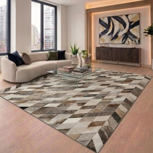 May include: A large, rectangular area rug with a geometric pattern of diamonds in shades of brown, beige, and gray. The rug is placed on a hardwood floor in a living room setting, with a curved sofa and glass coffee table.