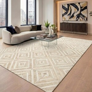 Könnte beinhalten: Ein großer rechteckiger Teppich mit einem sich wiederholenden geometrischen Muster aus konzentrischen Quadraten in Creme-, Beige- und Hellbrauntönen. Der Teppich besteht aus mehreren Paneelen mit texturiertem Material in Rautenform.